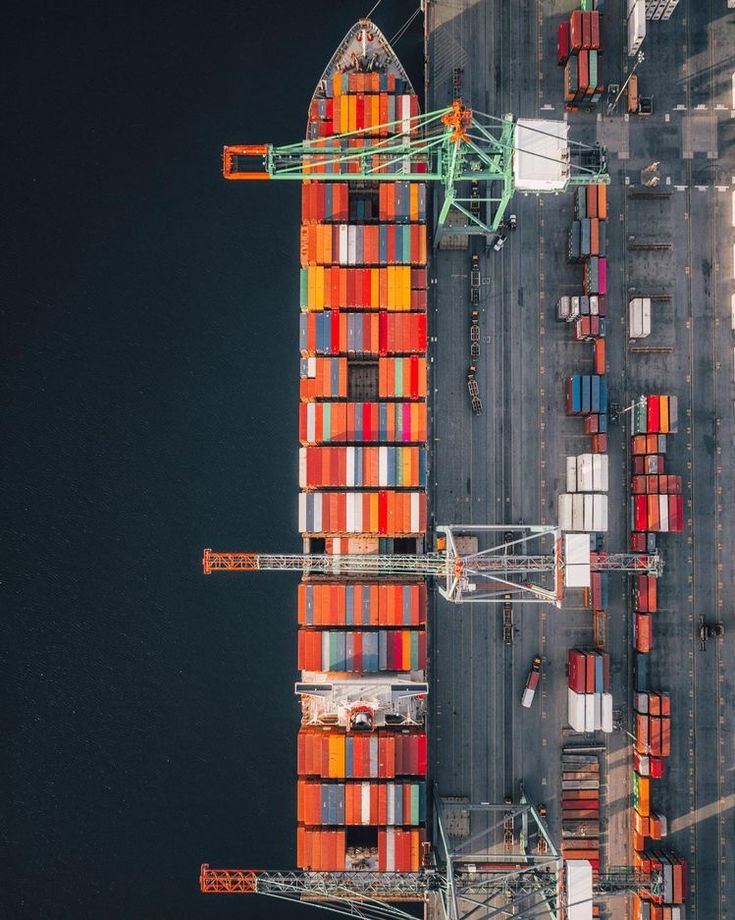 Vista aérea de um navio de contêineres atracado no porto, junto aos guindastes de carga
